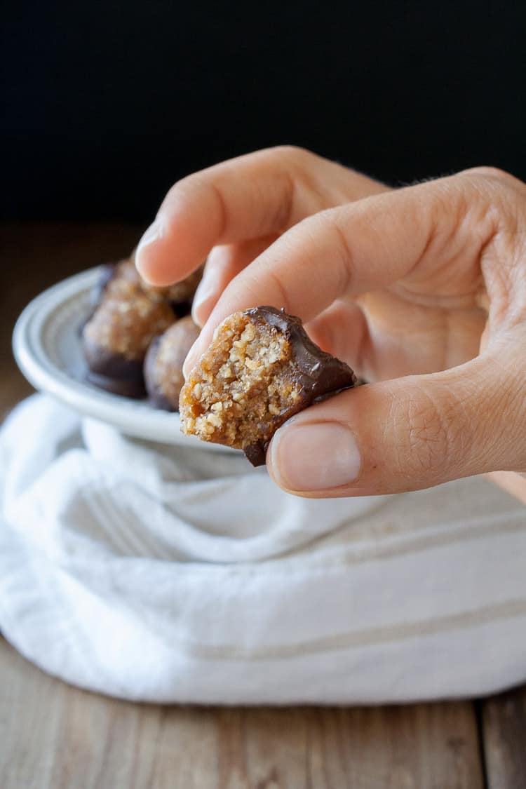 A hand picking up a Raw Vegan Caramel Peanut Protein Truffle