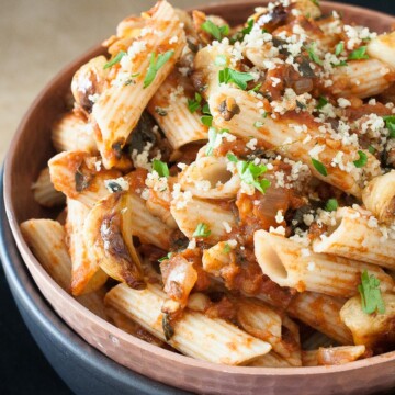 A close up of Chickpeas in Spicy Smoked Tomato Sauce with Penne in a blue bowl