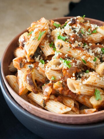 A close up of Chickpeas in Spicy Smoked Tomato Sauce with Penne in a blue bowl