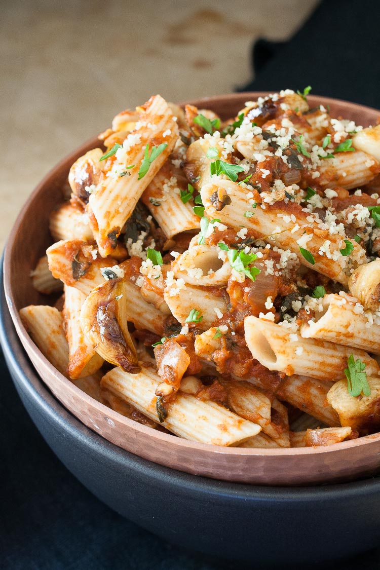 A close up of Chickpeas in Spicy Smoked Tomato Sauce with Penne in a blue bowl