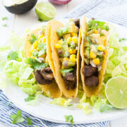 three tacos on a white plate topped with salsa