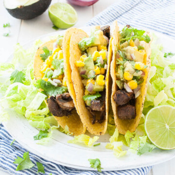 three tacos on a white plate topped with salsa