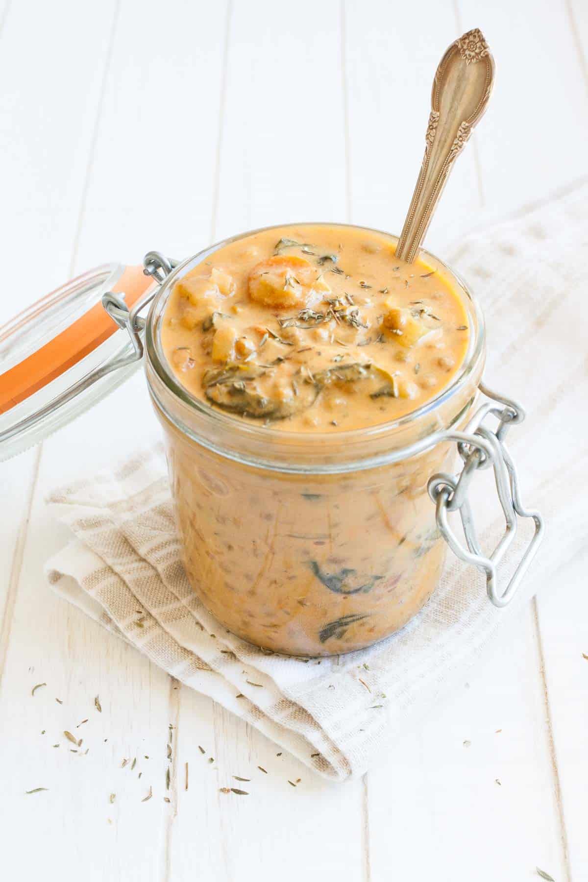 Top side view of orange colored lentil and veggie stew in a glass jar