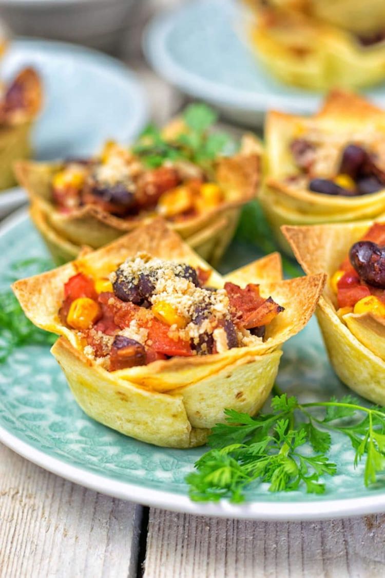 Crispy tortilla cups filled with beans and salsa on a light blue plate