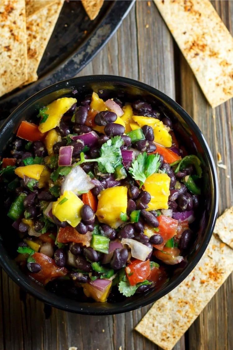 Top view of black bowl filled with black bean mango salsa topped with cilantro