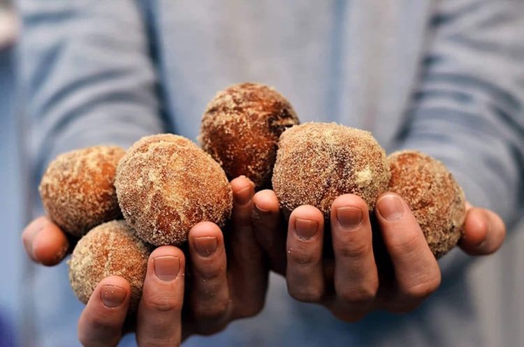 Front view of hands holding piles of brown sugar covered donut holes