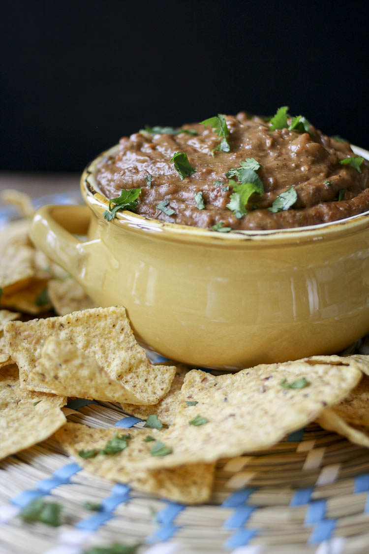 Close up of Mexican chili cheese dip in a yellow bowl surrounded by chips