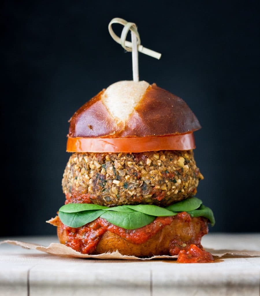 Vegan meatball burger on a pretzel bun with tomato and spinach