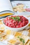 A spicy strawberry salsa in a bowl topped with chopped herbs