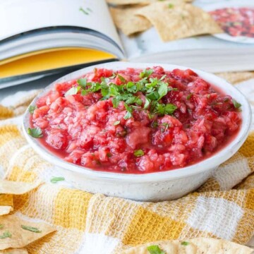 A spicy strawberry salsa in a bowl topped with chopped herbs