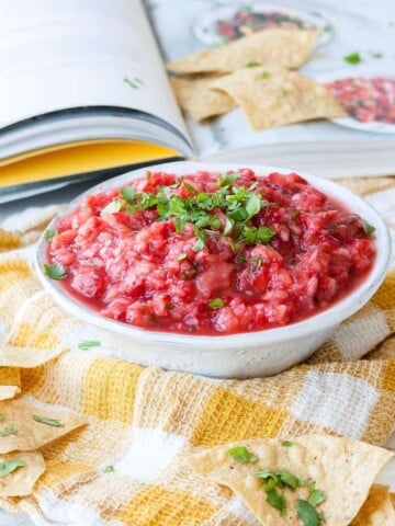 A spicy strawberry salsa in a bowl topped with chopped herbs