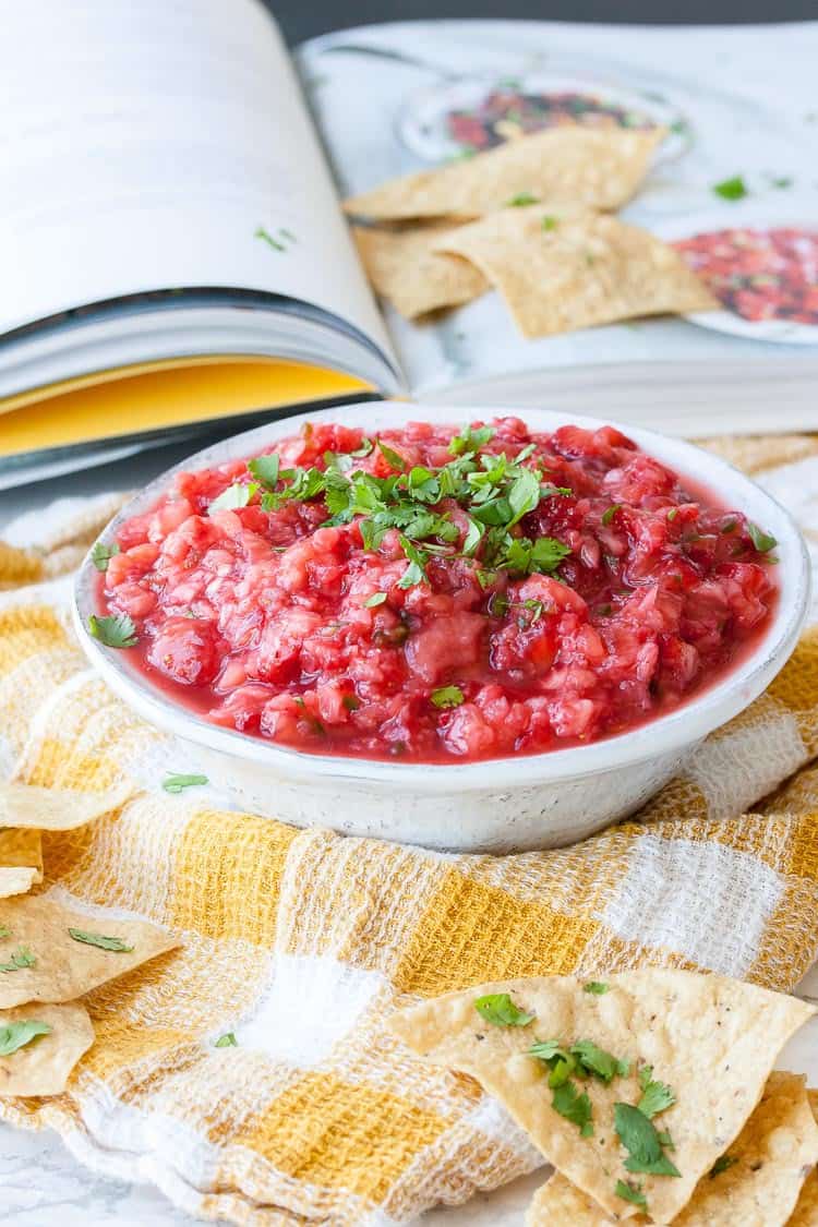 A spicy strawberry salsa in a bowl topped with chopped herbs