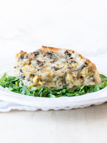 Spinach pie on a white plate on a bed of sautéed spinach