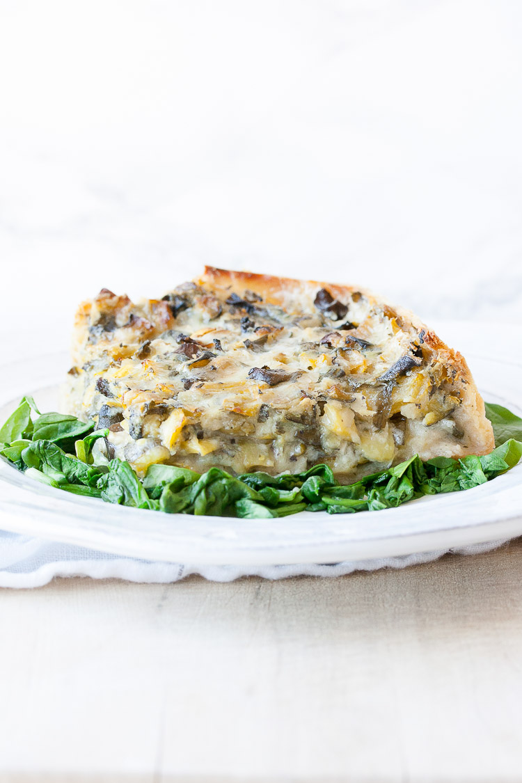 Spinach pie on a white plate on a bed of sautéed spinach