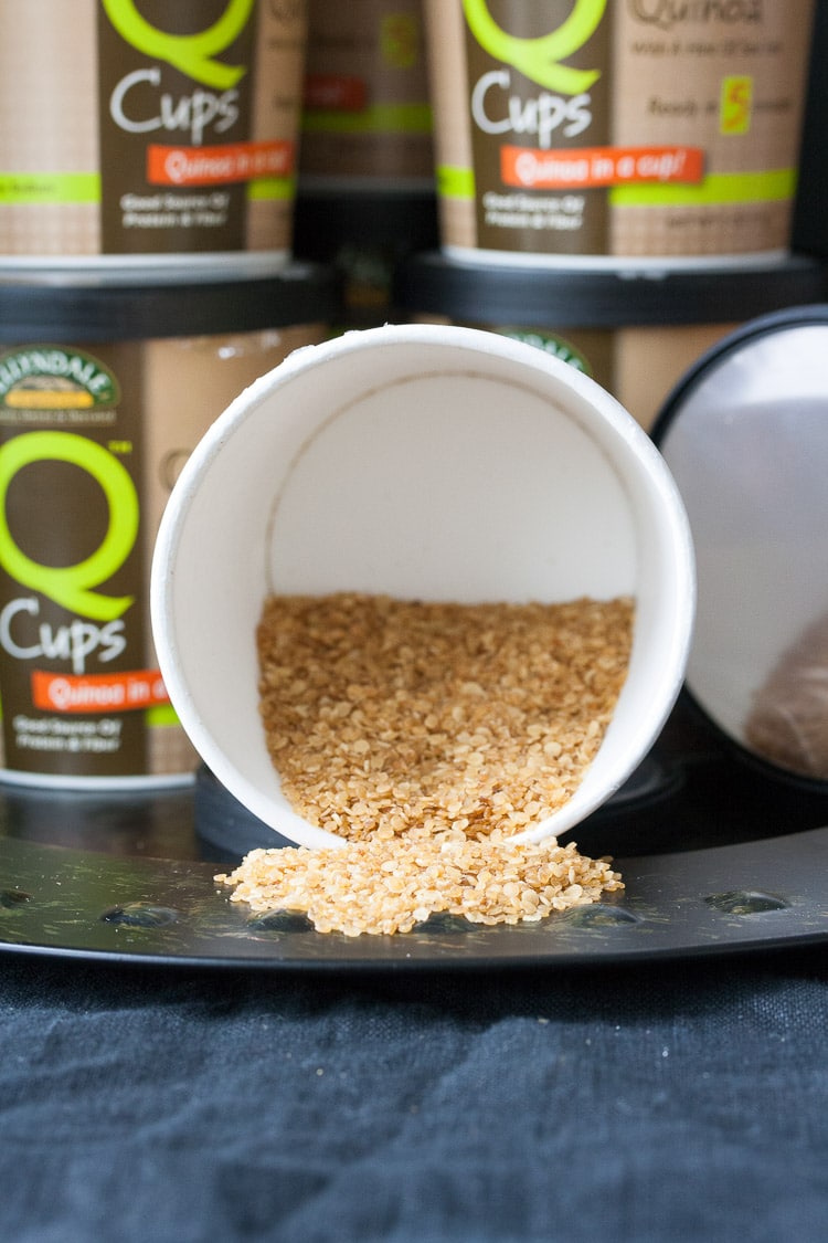 A tub of uncooked quinoa spilling out onto a black plate