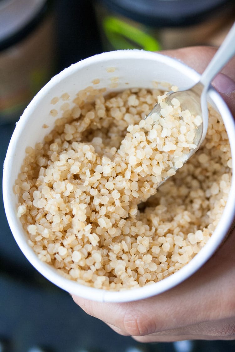 A close up of quinoa in a tub with a spoon