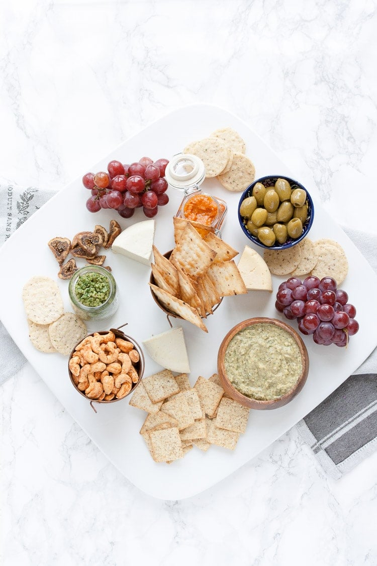 An overhead shot of a vegan cheese and dip platter on a marble surface