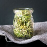 Pesto quinoa dip in a jar with a dark backdrop