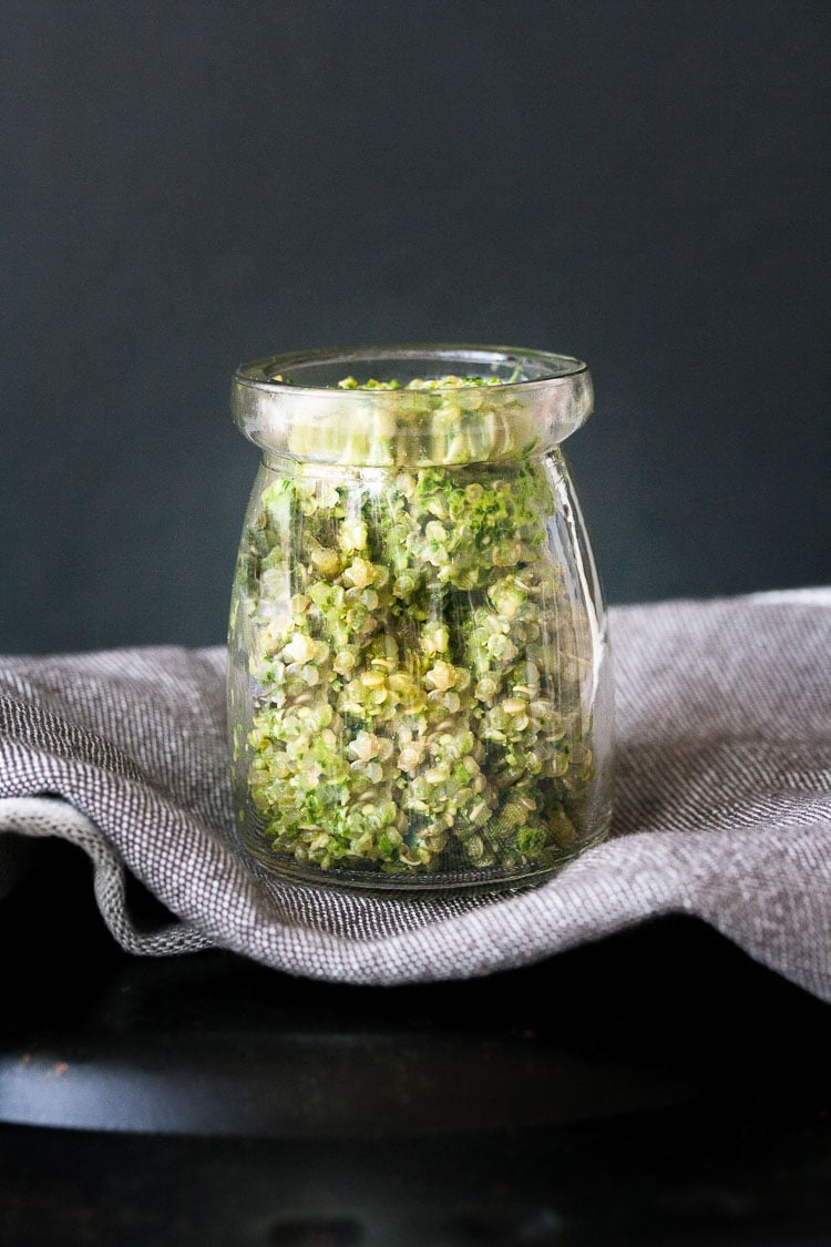 Pesto quinoa dip in a jar with a dark backdrop