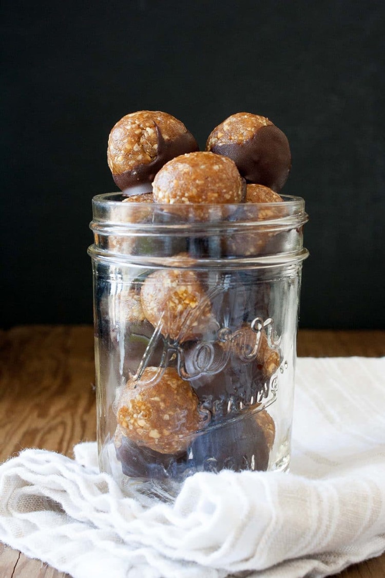 a glass jar filled with vegan peanut butter truffles half dipped in chocolate