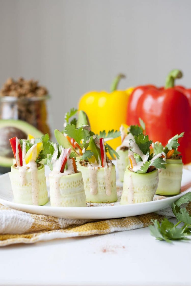 a side view of rolled zucchini appetizers on a white serving plate