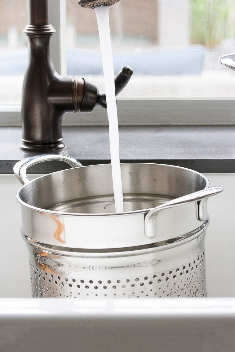 A pasta pot in a sink getting filled with water to make a Mexican pasta salad