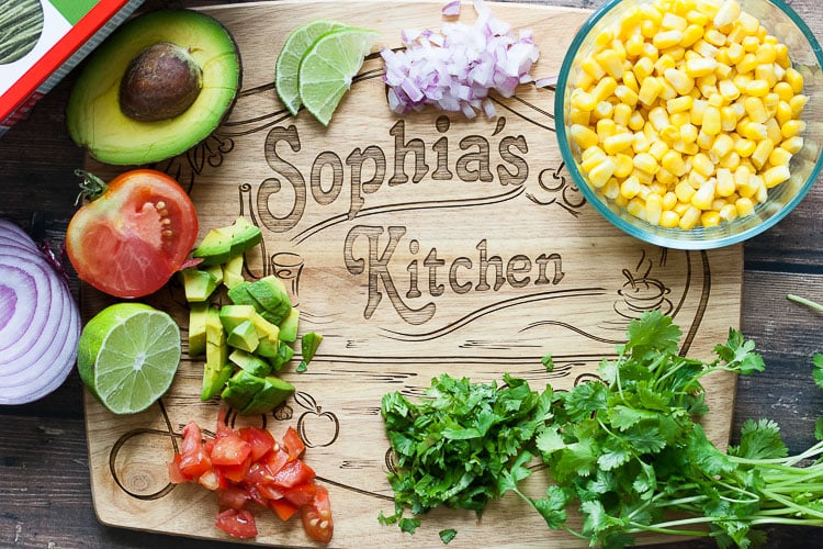 An overhead shot of a cutting board with ingredients all around it to make a mexican pasta salad