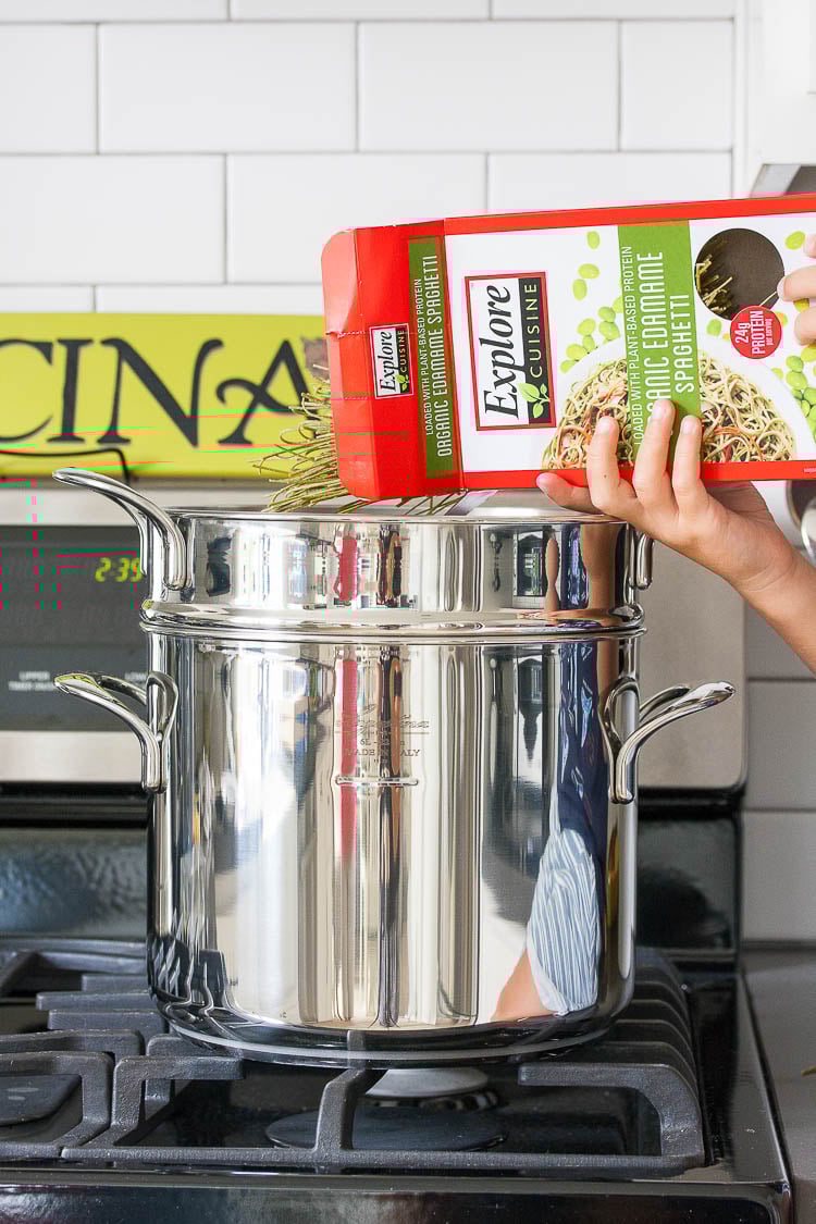 Edamame noodles getting added to a pot of water to make a Mexican pasta salad