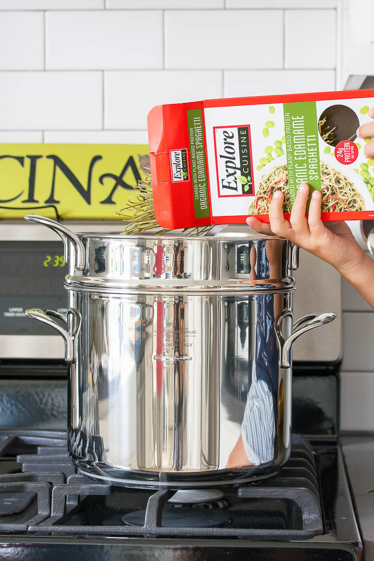 Edamame noodles getting added to a pot of water to make a Mexican pasta salad