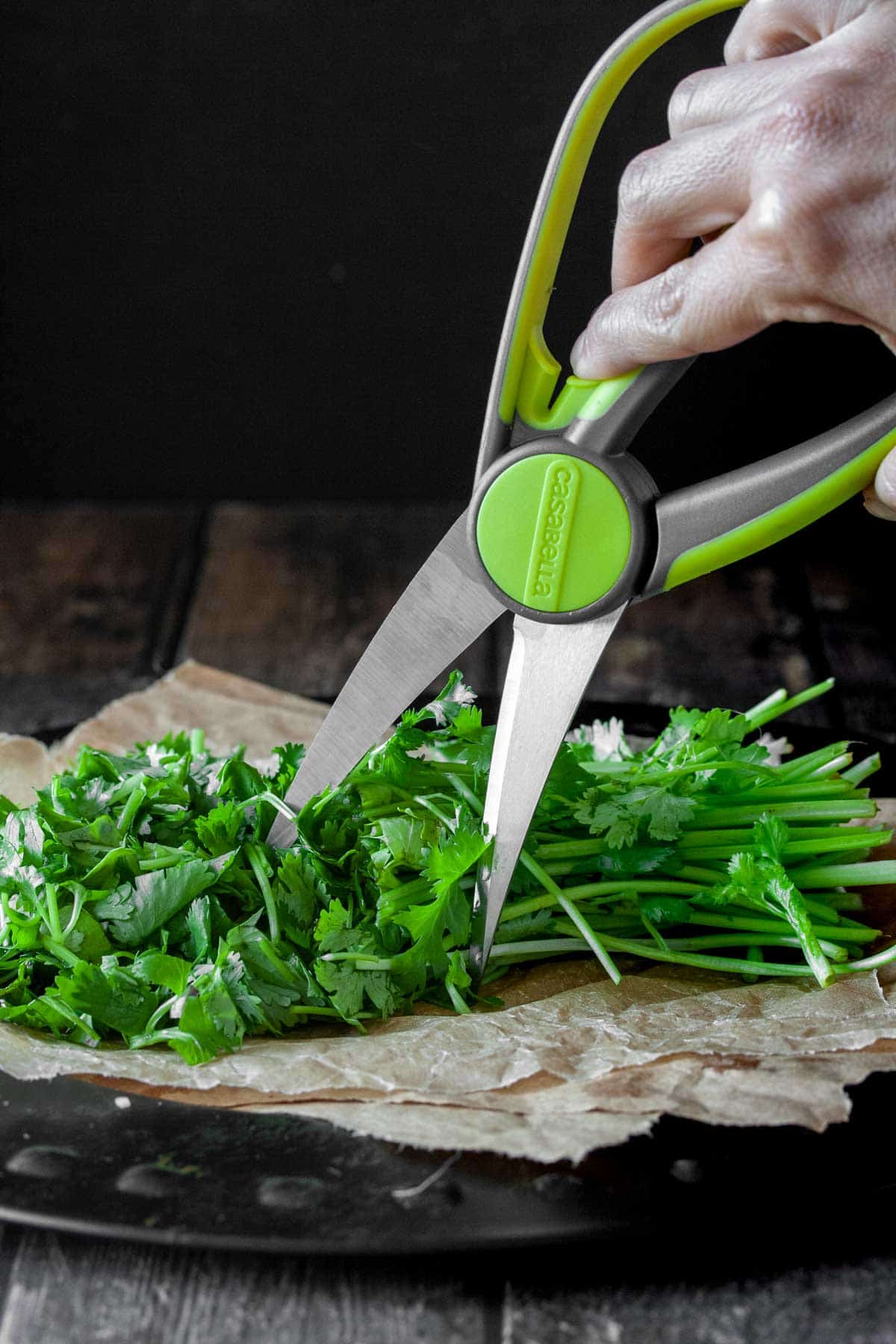 kitchen shears cutting cilantro for making a loaded guacamole dip with vegan cotija cheese
