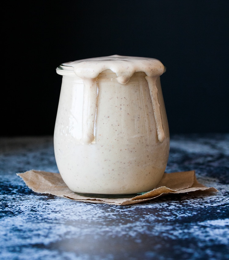 Low fat maple mustard tahini sauce in a glass jar and slightly overflowing