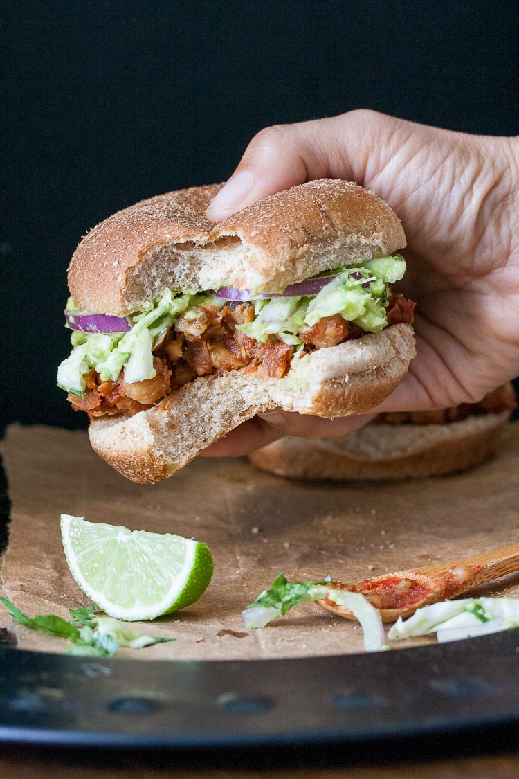 A hand holding a vegan bbq slider with a bite out