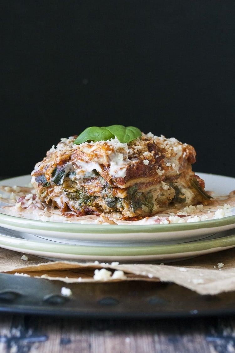 Piece of vegan creamy pesto and sausage lasagana on two stacked plates