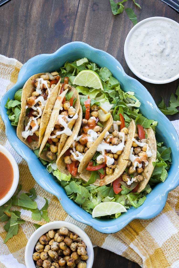 Top view of baking pan with five buffalo chickpea tacos on a bed of lettuce