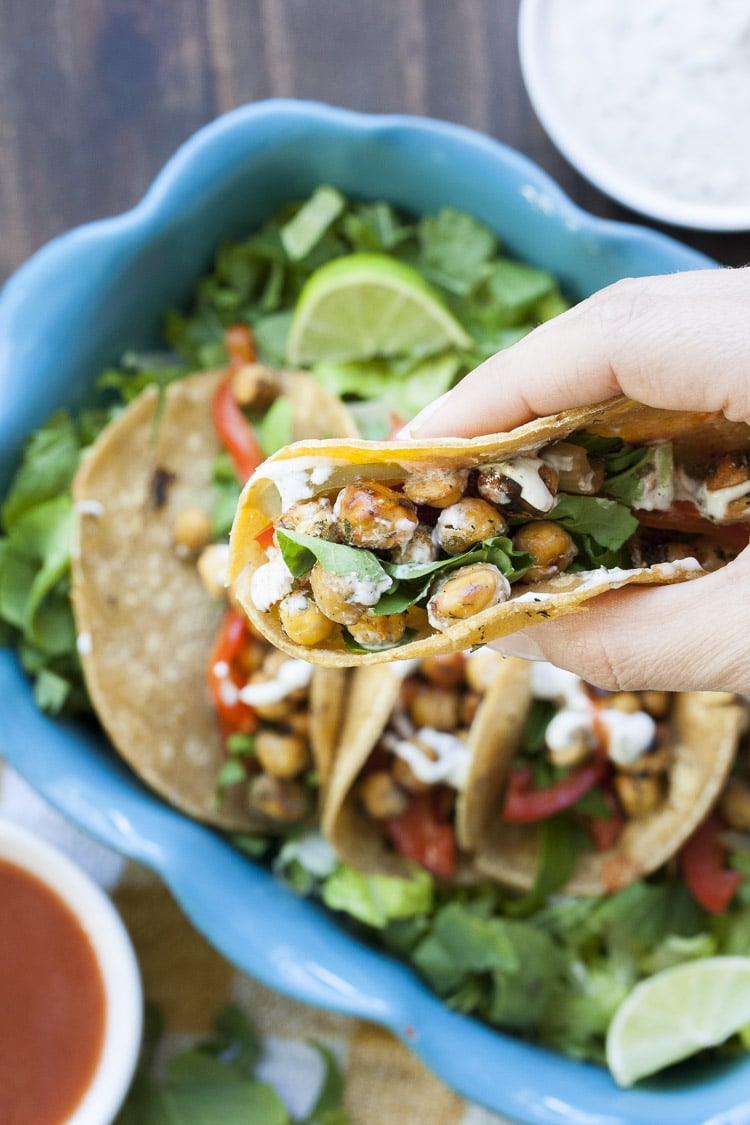 Top view of hand holding a buffalo chickpea taco with lettuce and ranch sauce