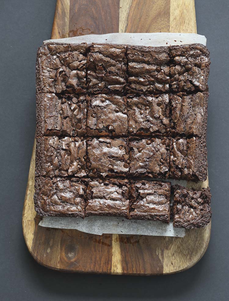 Top view of brownies cut into sixteen squares sitting on a wooden board