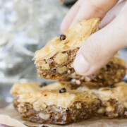 Hand grabbing a piece of Greek vegan baklava off of a stack of baklava