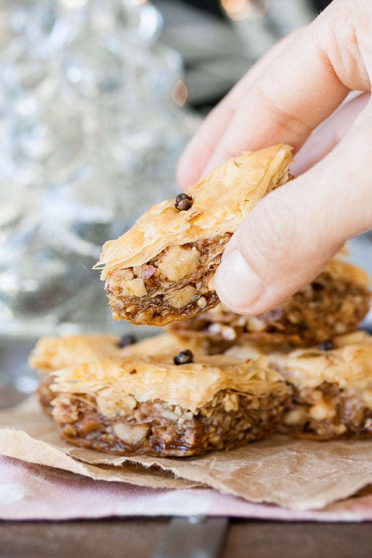 Hand grabbing a piece of Greek vegan baklava off of a stack of baklava