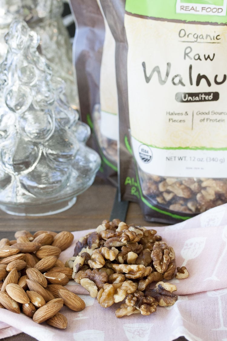 A pile of almonds next to a pile of walnuts on a pink napkin