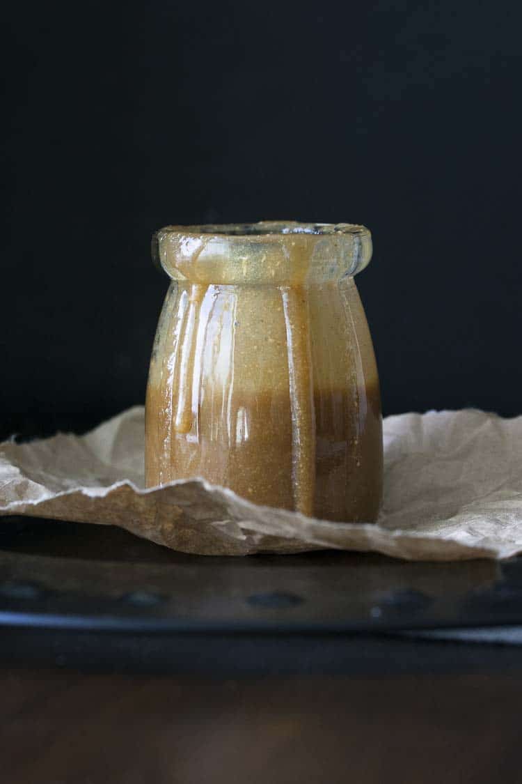 Salted peanut butter caramel in a glass jar with some dripping down the sides