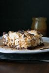 A slice of vegan dessert lasagna on a white plate drizzled with caramel sauce