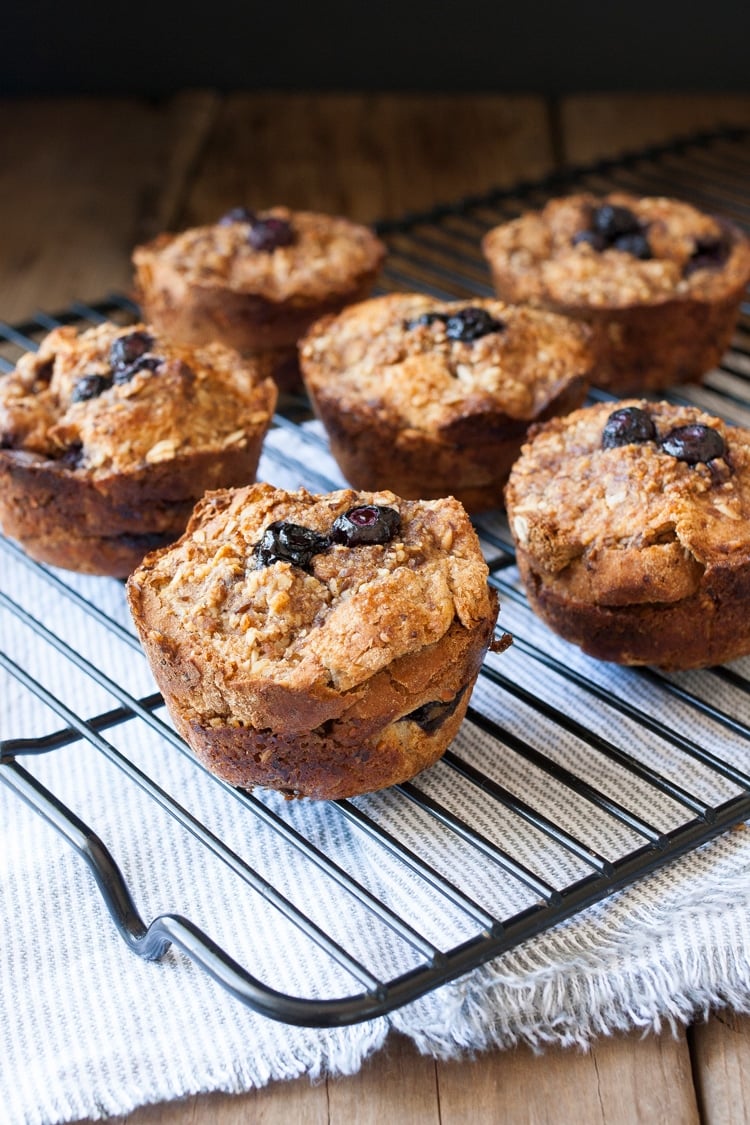 Wire cooling rack filled with blueberry french toast muffins sitting on grey striped towel