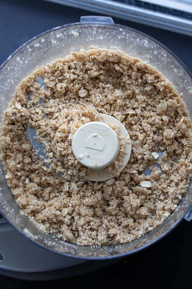 Top view of a food processor with a pulsed oats and flour mixture