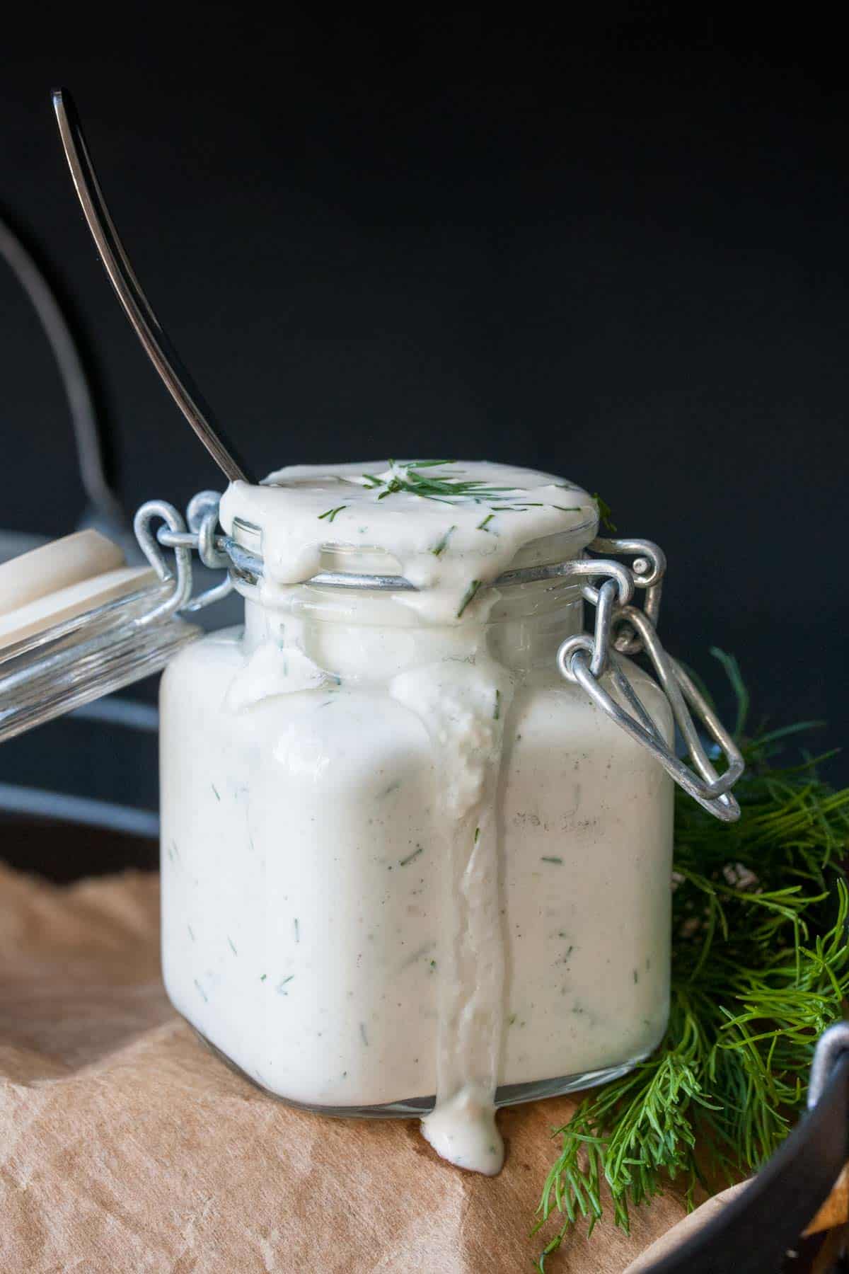 Glass jar on parchment filled with vegan greek tzatziki