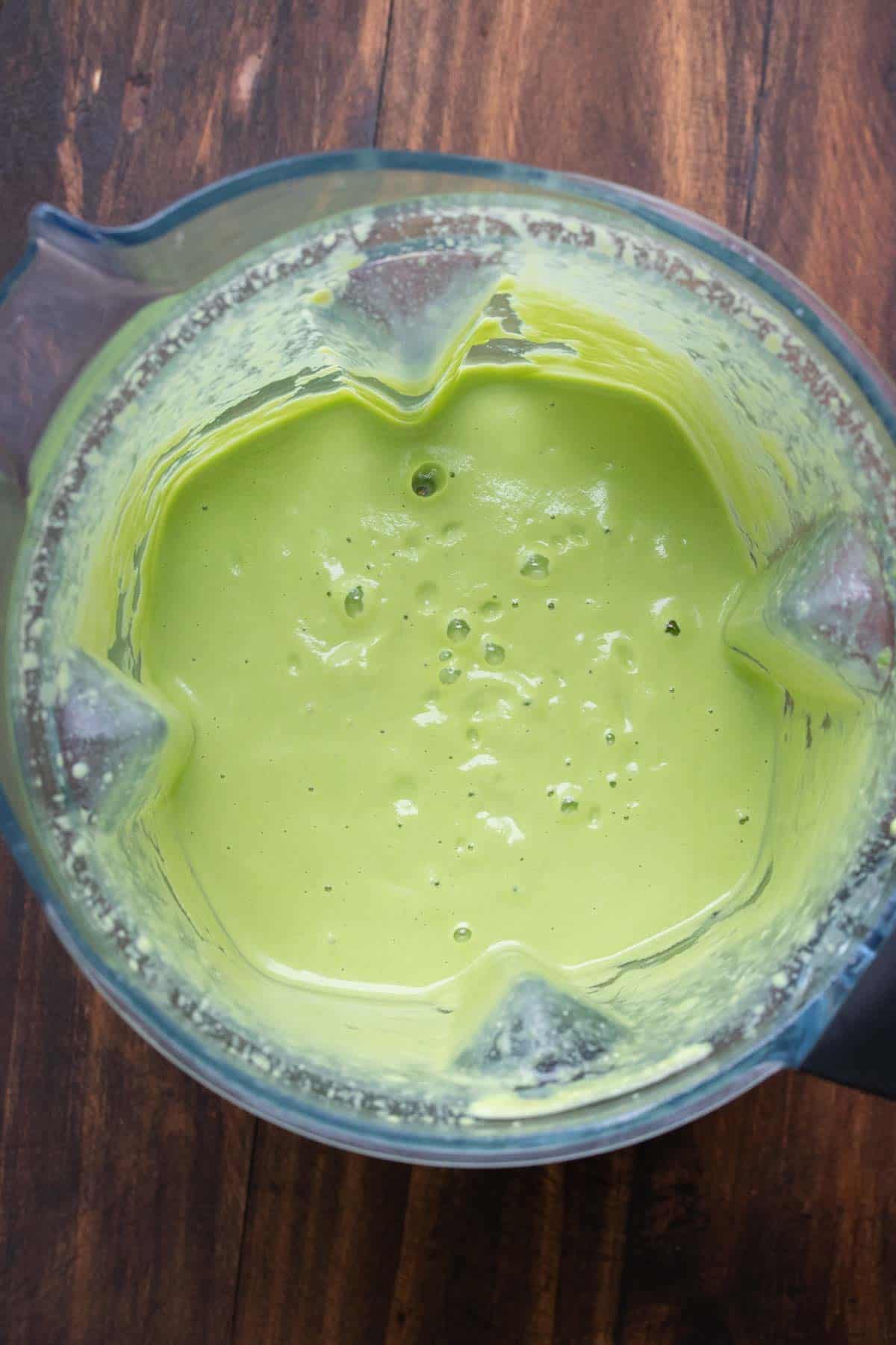 Top view of blender filled with creamy green sauce.