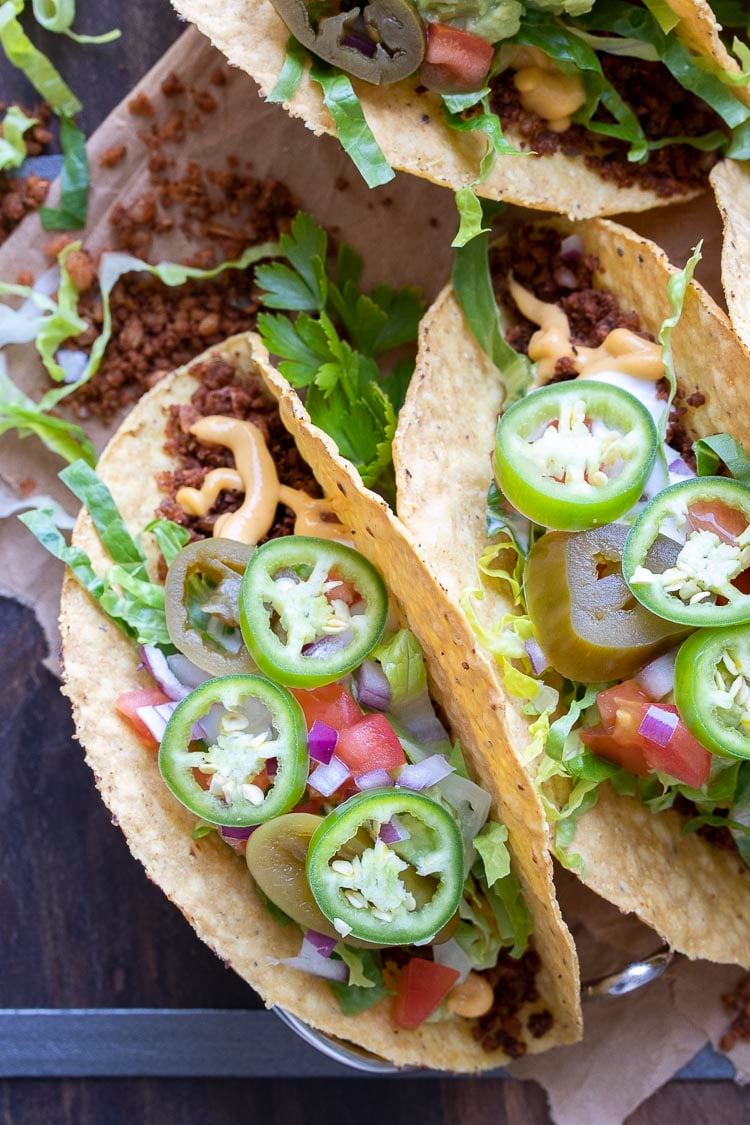 Front view of a crispy taco with vegan taco meat crumbles and lots of toppings