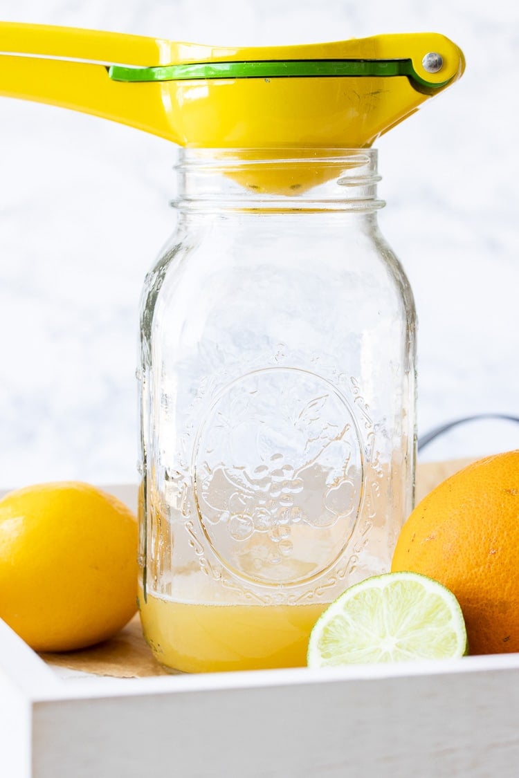 Citrus squeezer juicing citrus fruit into a glass jar