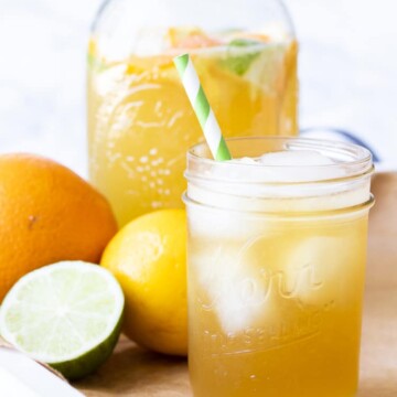 White tray with sparkling citrus tea over ice next to citrus fruit