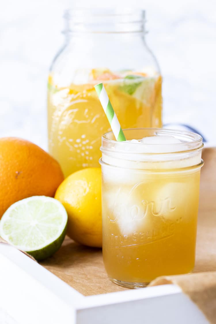 White tray with sparkling citrus tea over ice next to citrus fruit