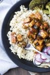 Close up of fork in brown rice with General Tso's tofu